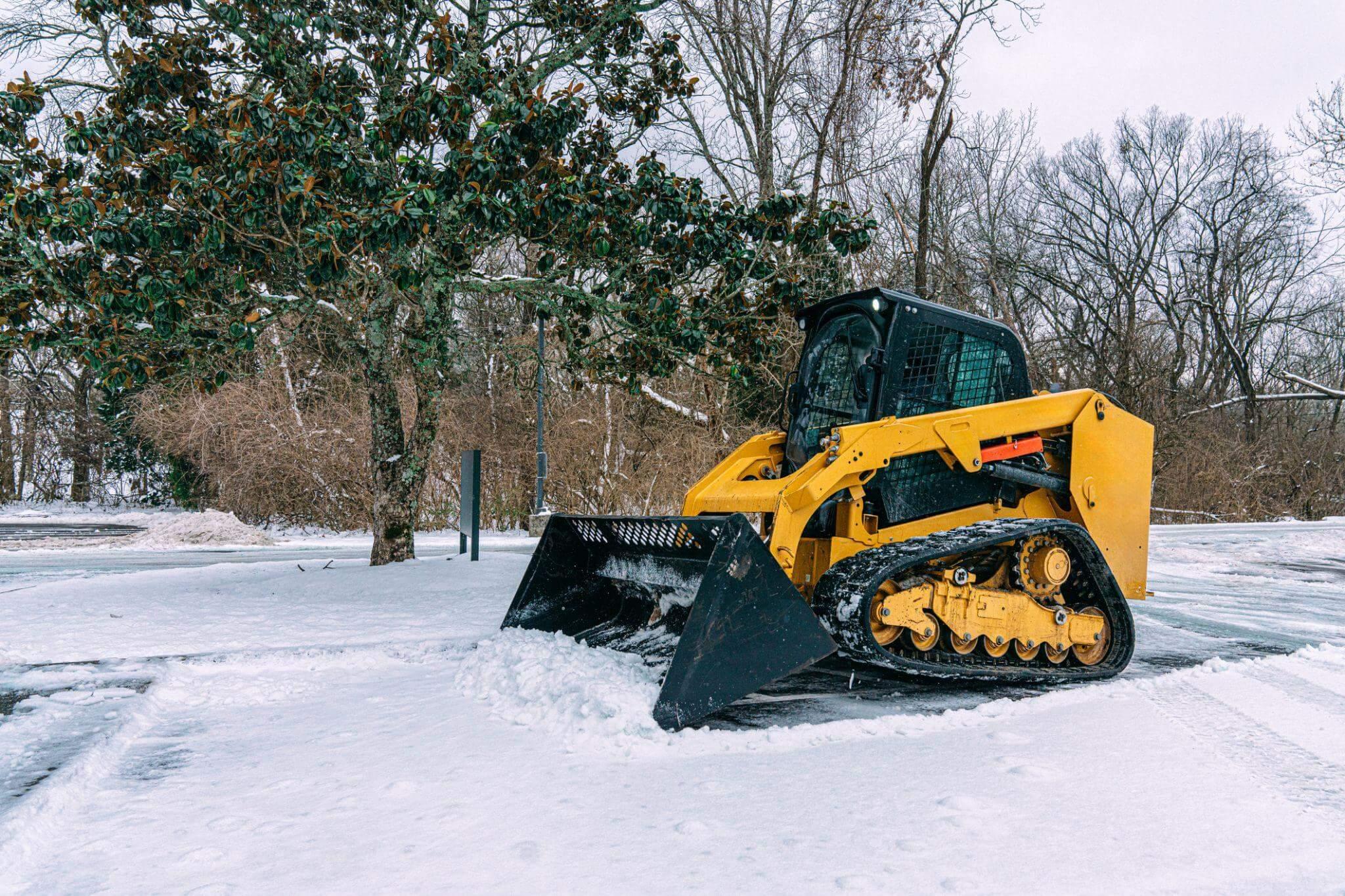 A yellow bulldozer used for snow removal parked in snowy landscape
